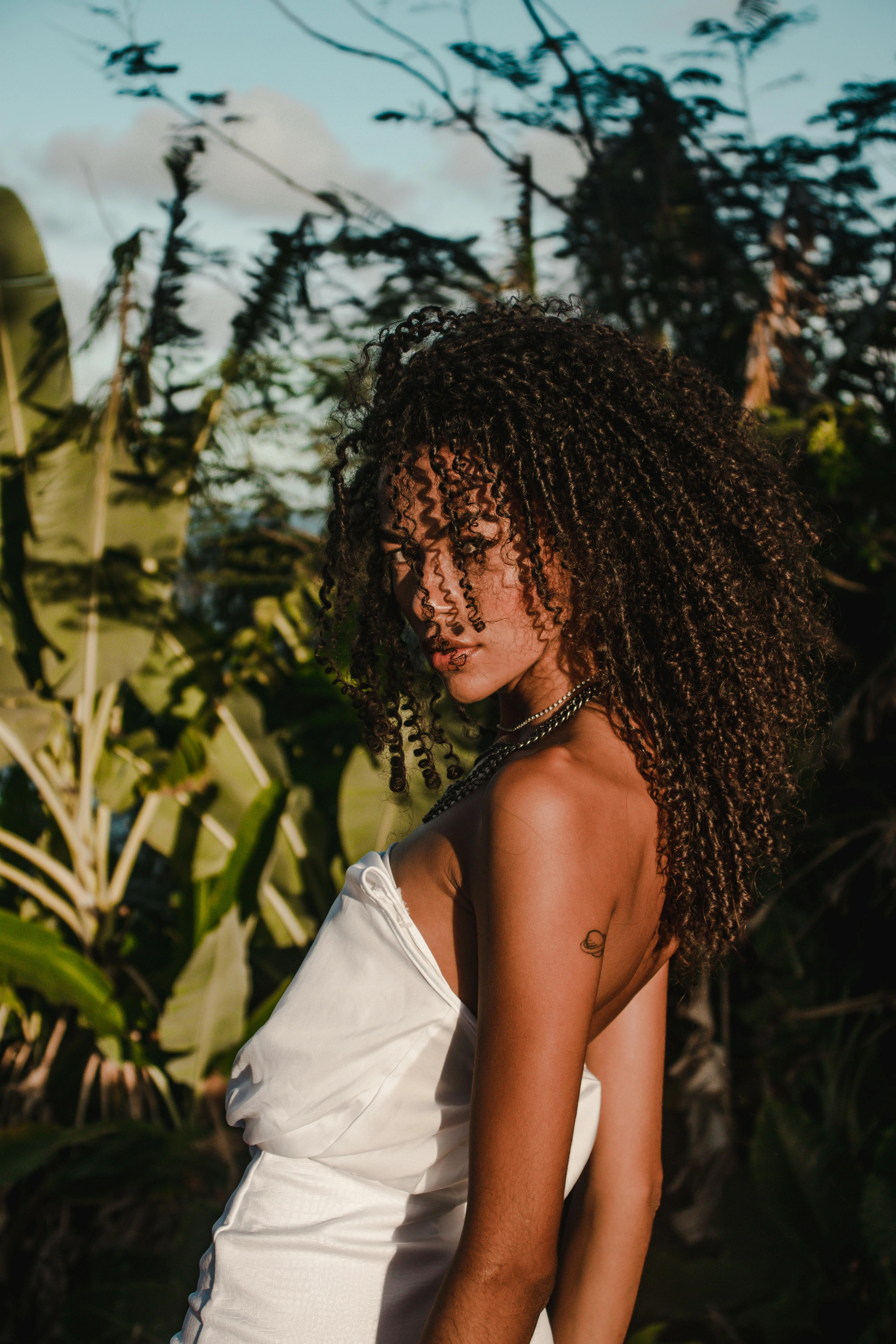 Latin fashion model in white dress posing in tropical setting