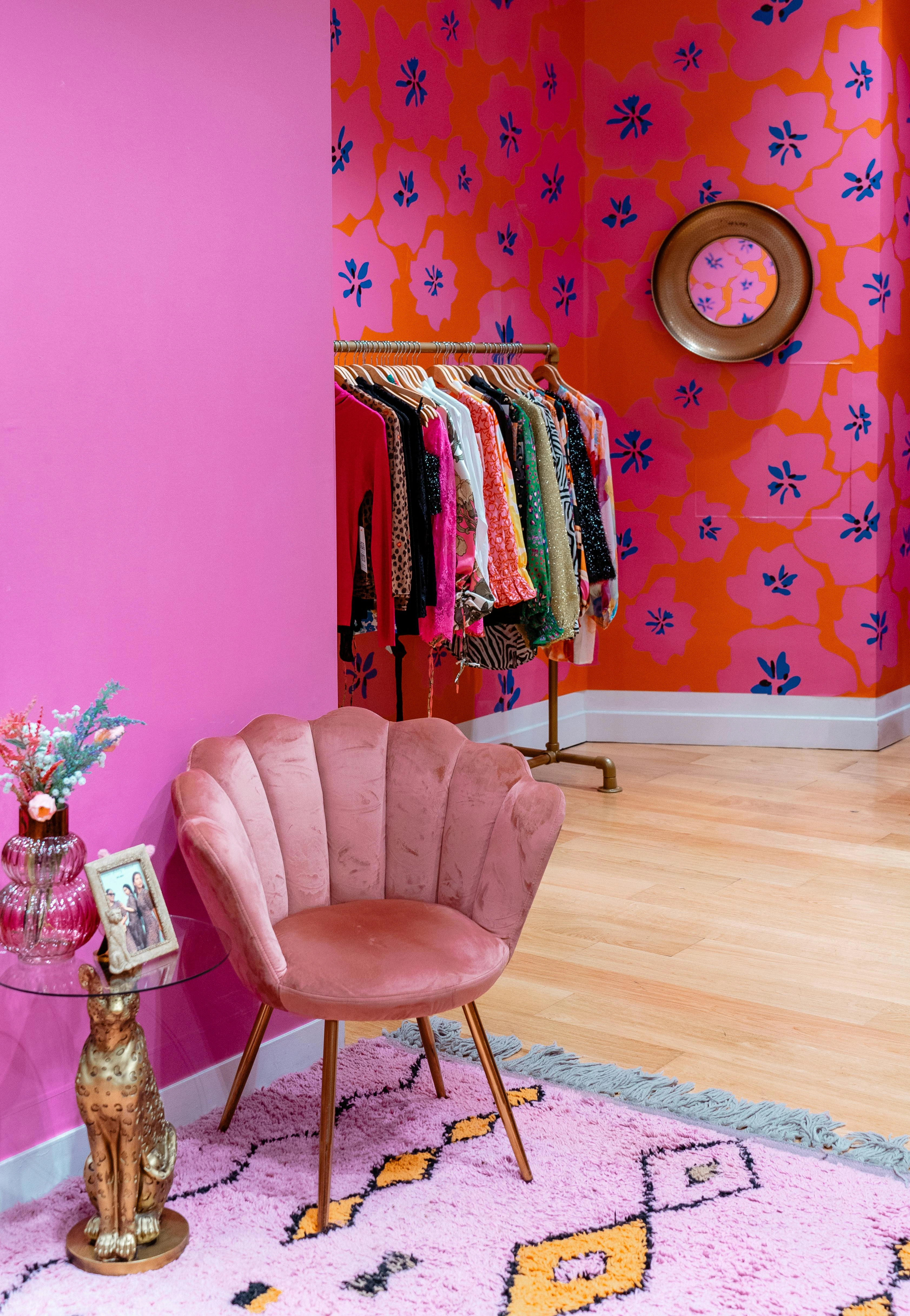 Pink fashion boutique interior with velvet chair and clothing rack